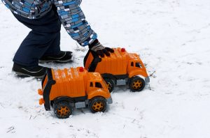 Child playing with trucks in snow